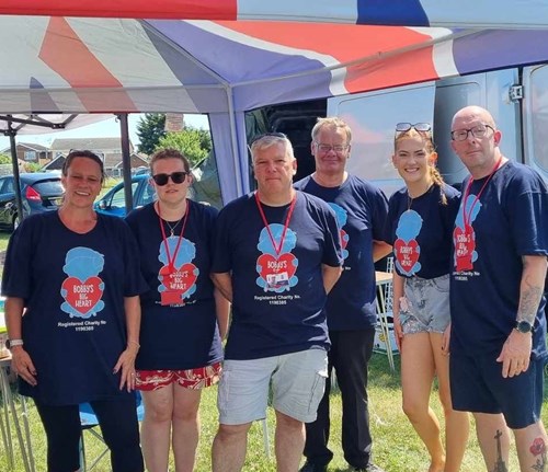 Group of people standing outside smiling at the camera.
