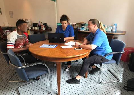 Photo of Carmalita Njie and Izabela Jachimowicz with a young man seeking asylum