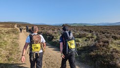 Two men walking in open fields.