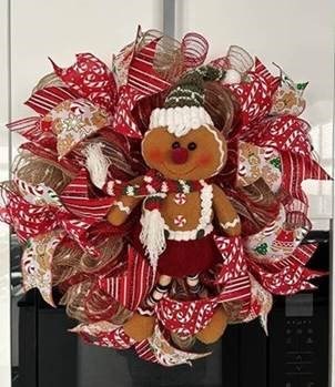 A red handmade Christmas Wreath with a gingerbread teddy in the middle 