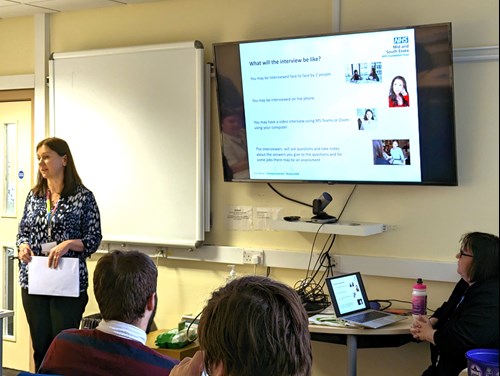 A woman standing at the front of a group of people giving a presentation about recruitment and careers