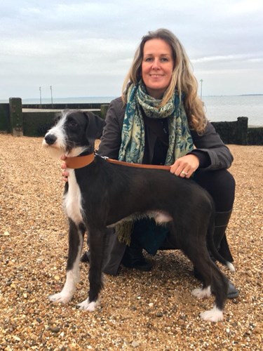 White woman on the beach with black and white dog. 