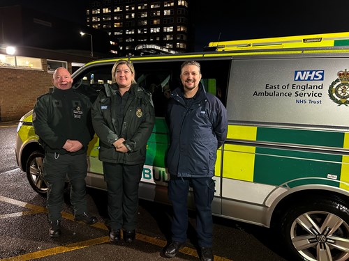 Three clinicians and mental health professionals in uniform standing in front of a mental health response car.
