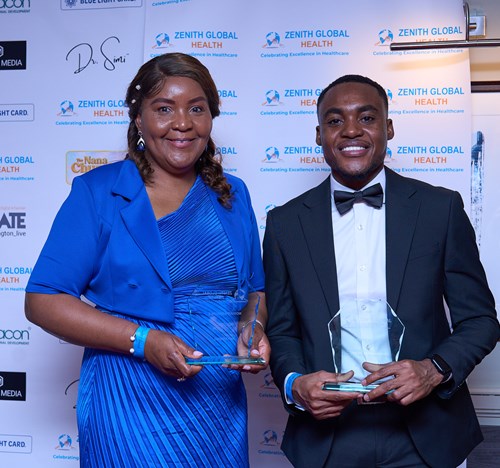 A black man and woman at an award ceremony. They are dressed in fancy clothes and holding awards.