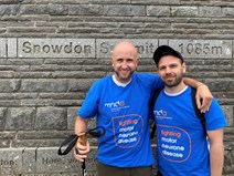 Two white men standing at Snowdon mountain summit.