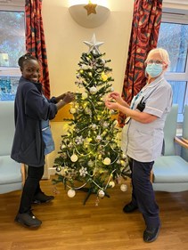 Two staff members decorating a Christmas tree.