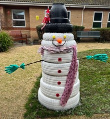 Snowman made out of white tyres with a hat and scarf.