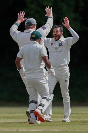 Three cricket players on the field cheering.