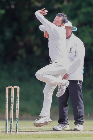 Action shot of a man bowling a cricket ball. 