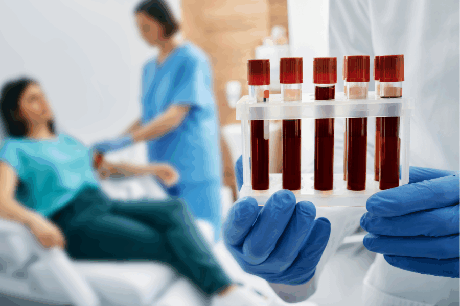 Woman having a blood test. Focus on 5 test tubes filled with blood samples.