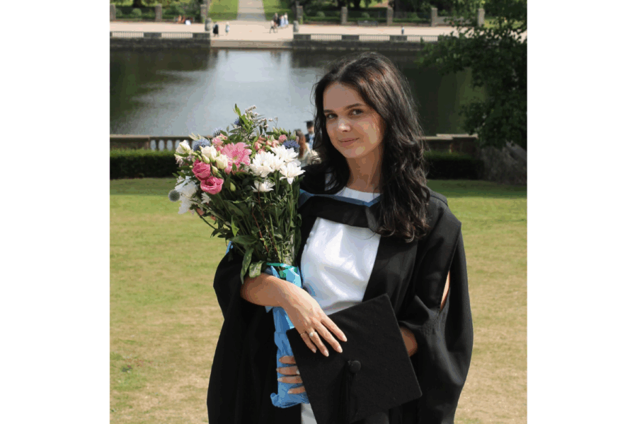 Photograph of Louisa in her graduation gown, holding a bouquet of flowers.