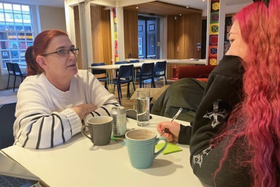 Two people in a coffee shop, talking over a drink.