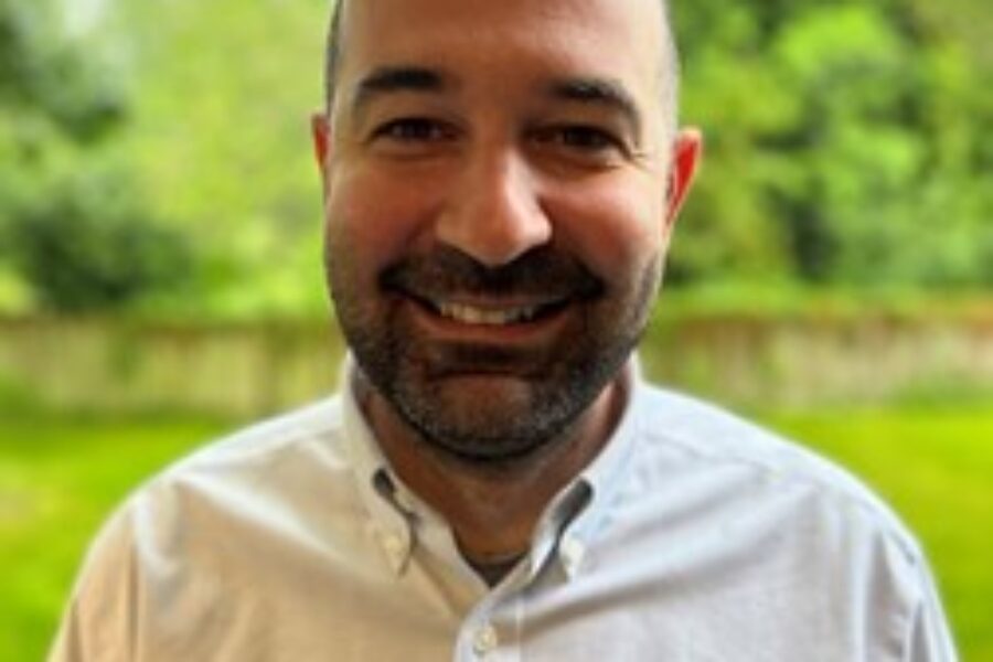 Man standing outside, smiling at the camera.