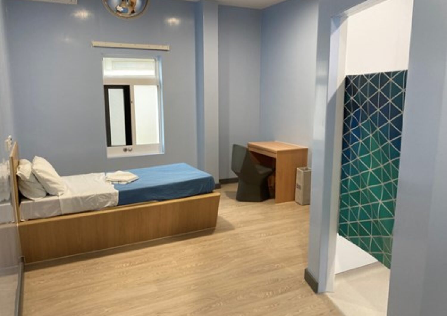 Inpatient ward bedroom with a bed, desk and ensuite bathroom