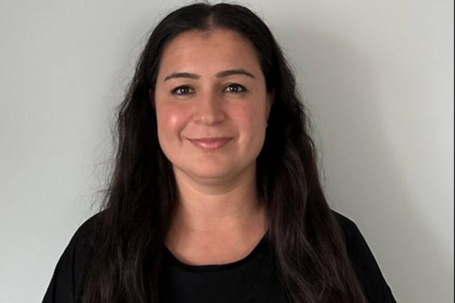 Nursac Durmus, long black hair, wearing a black top, smiling at the camera.