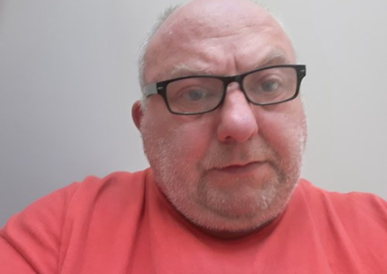 Simon Cross, wearing an orange top, wearing glasses.